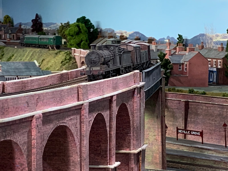 Model steam goods train crossing viaduct