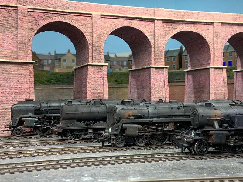 Weathered Bachmann steam locomotives on shed next to viaduct